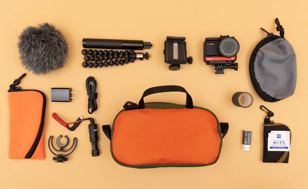 A Texturized Orange Grab Bag surrounded by photo equipment including a Small Ghost Whale Pouch in Orange 152, a Small Q-Kit in Cloud 525d Ballistic, and a Super Mini Ghost Whale Pouch in Black with Coyote Zipper.